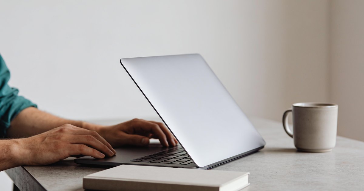 Hands on a desk during WordPress maintenance, notebook, and laptop